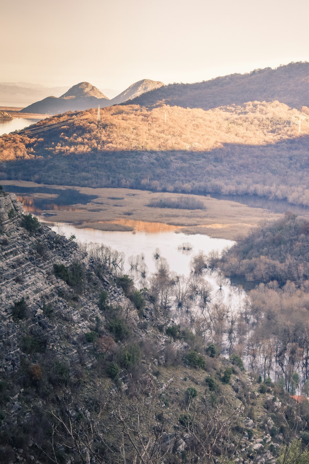 a view of a lake and mountains from the top of a hill