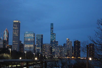 Elegant nighttime city skyline with illuminated financial district buildings under a deep blue sky.