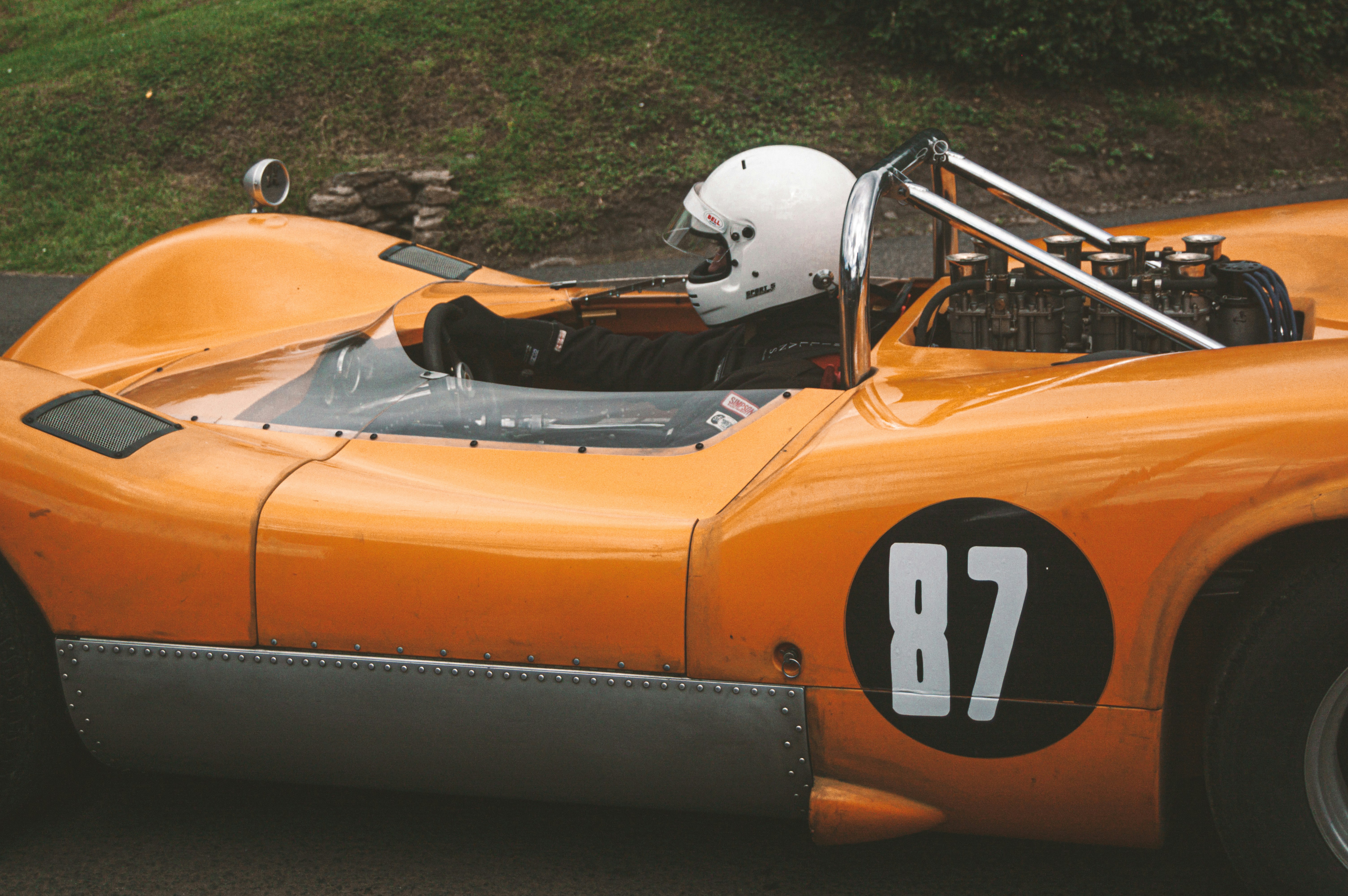 an orange race car with a white helmet on top