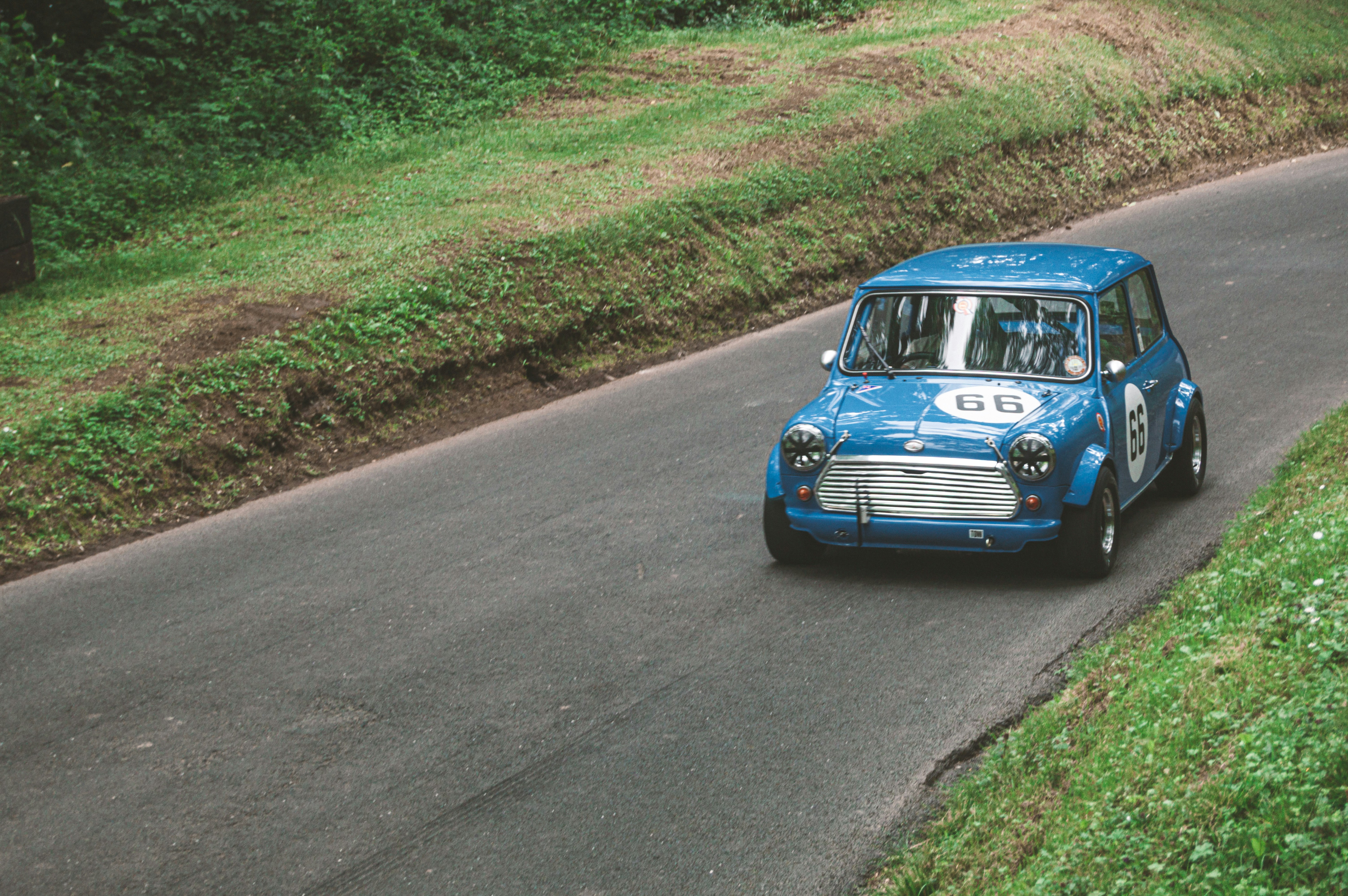 a small blue car driving down a country road