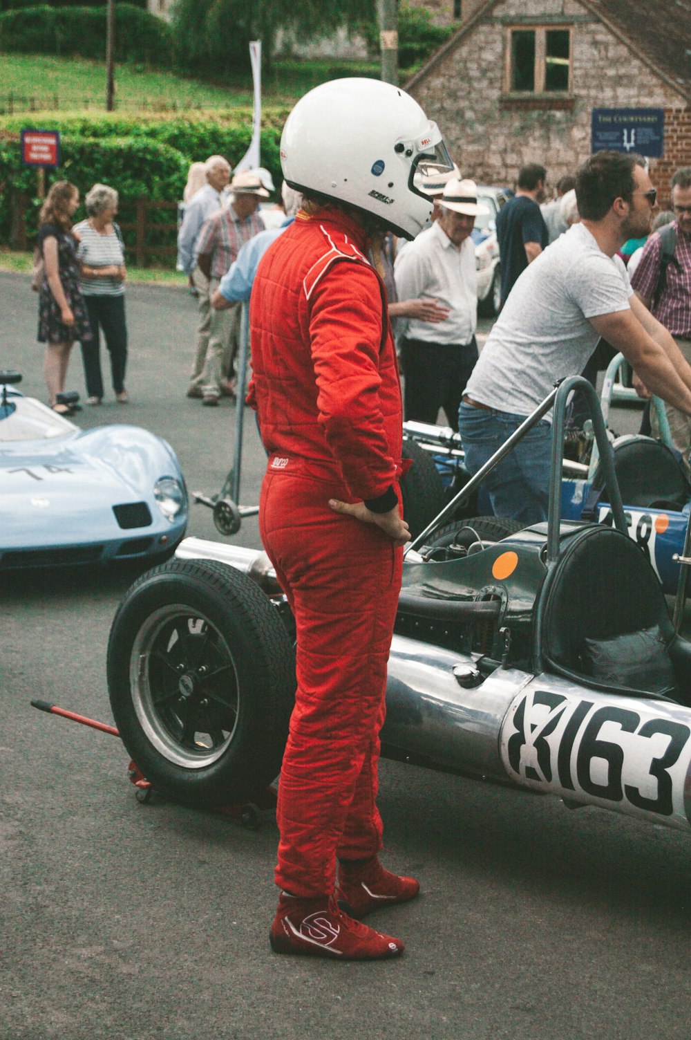 a man in a racing suit standing next to a race car