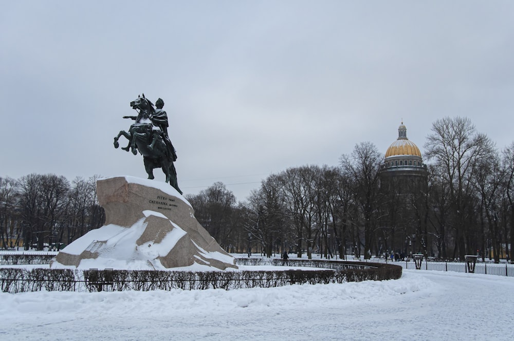 a statue of a man riding a horse in the snow