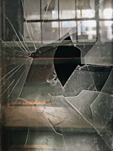 a broken glass window with a hole in it