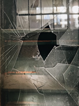 a broken glass window with a hole in it