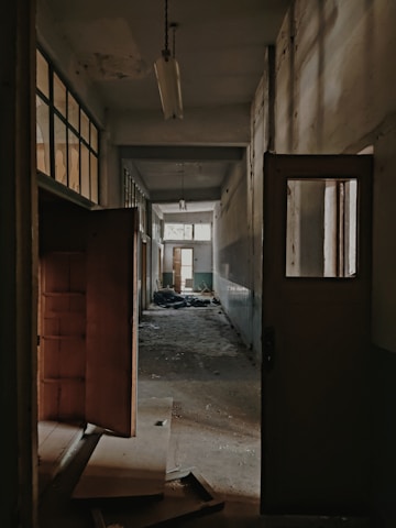 A dimly lit empty hallway with peeling walls.