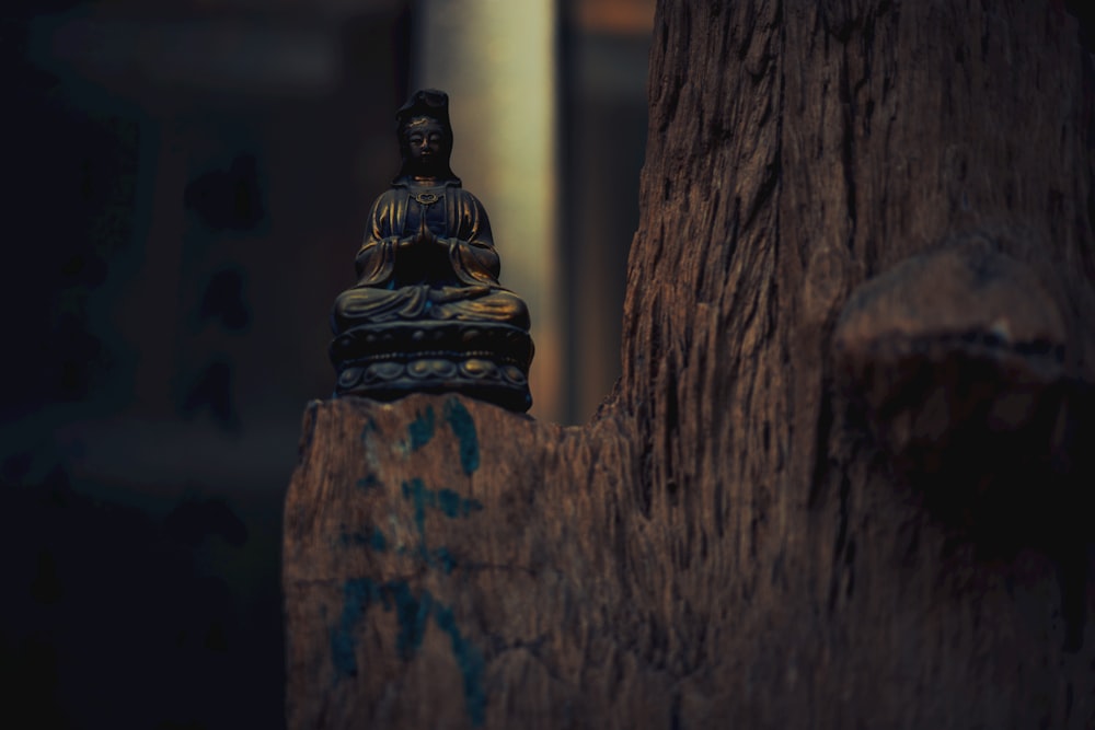 a buddha statue sitting on top of a tree stump