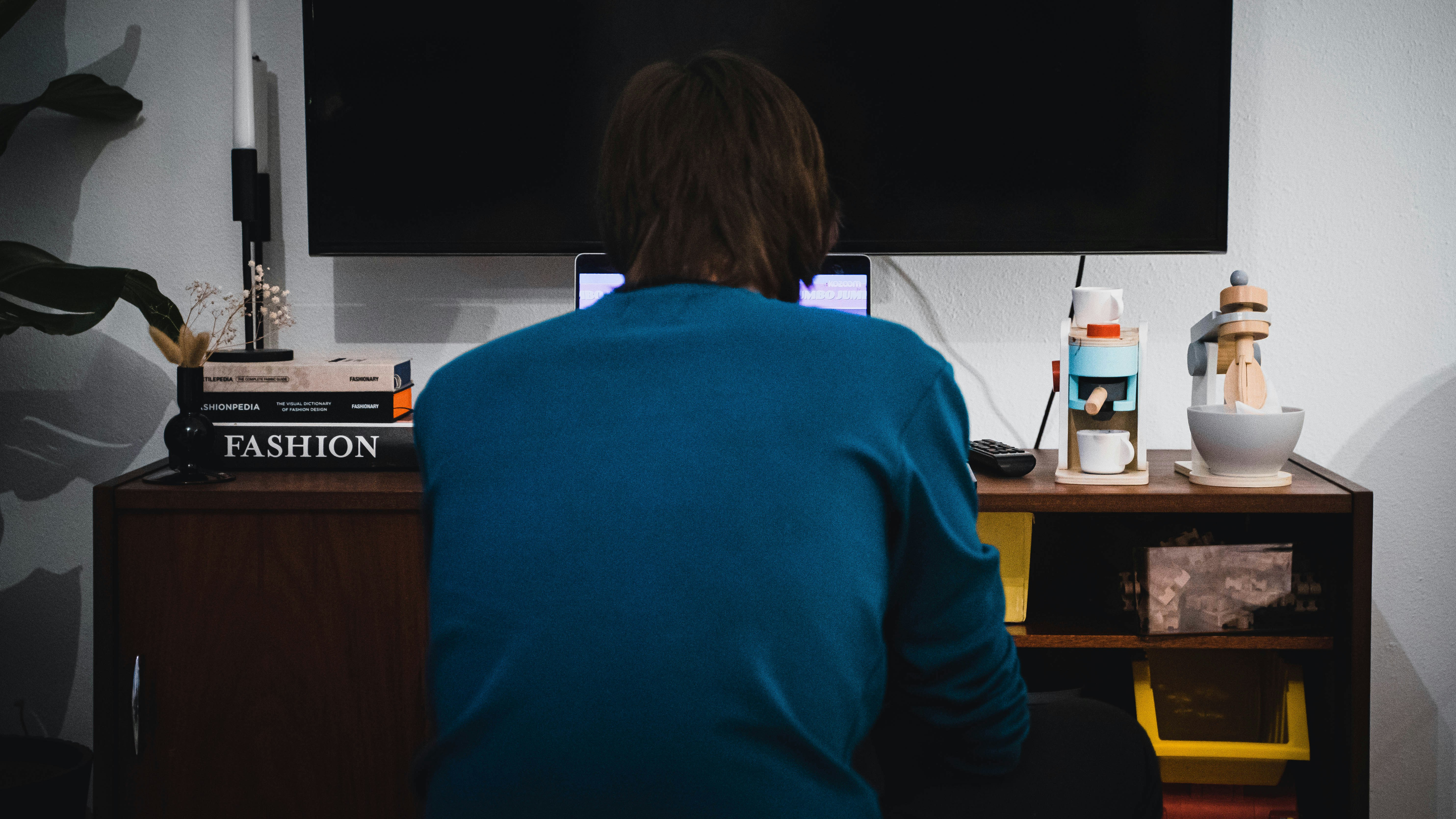 a person sitting at a desk in front of a television