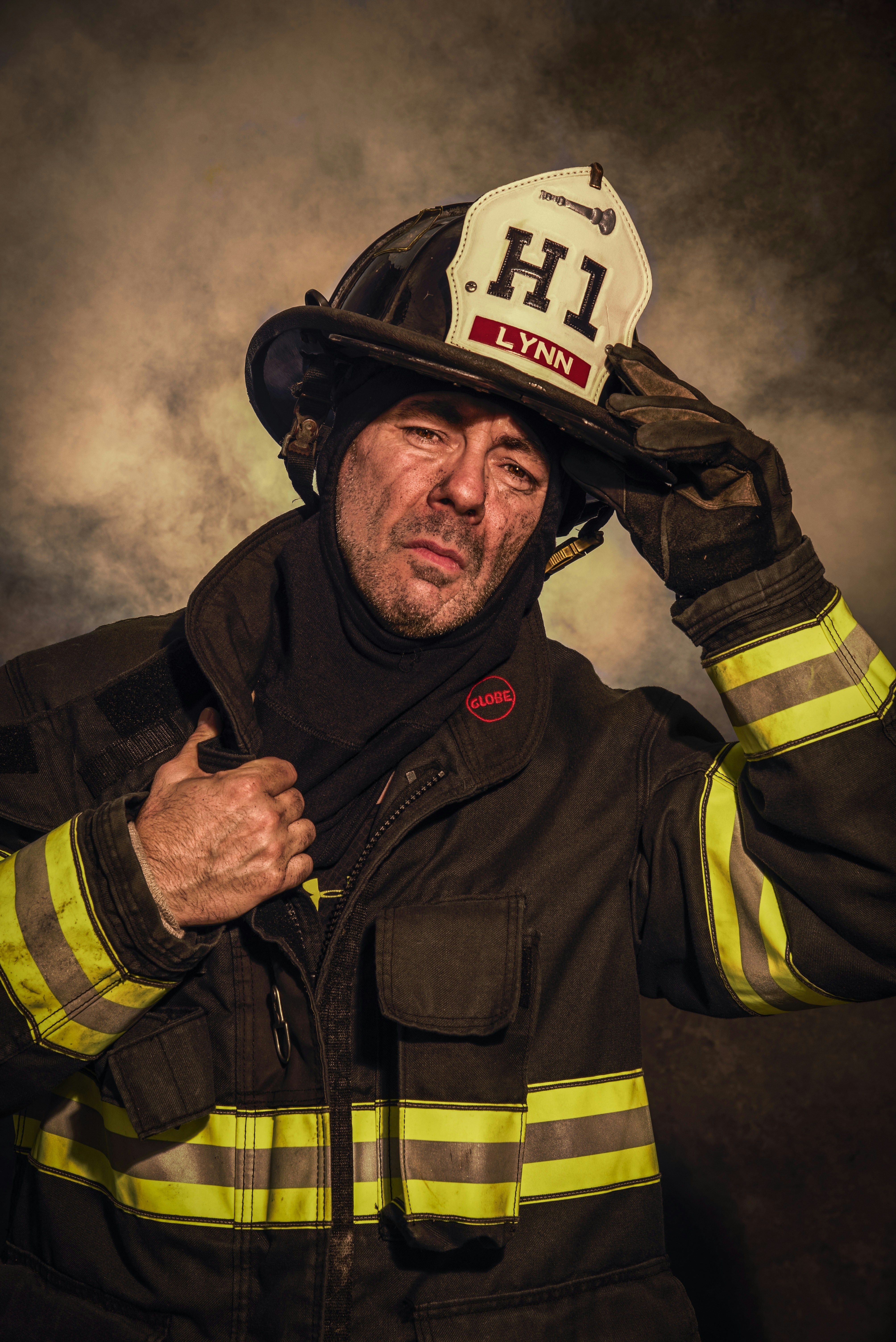 A man in a fireman's uniform holding his hat over his head