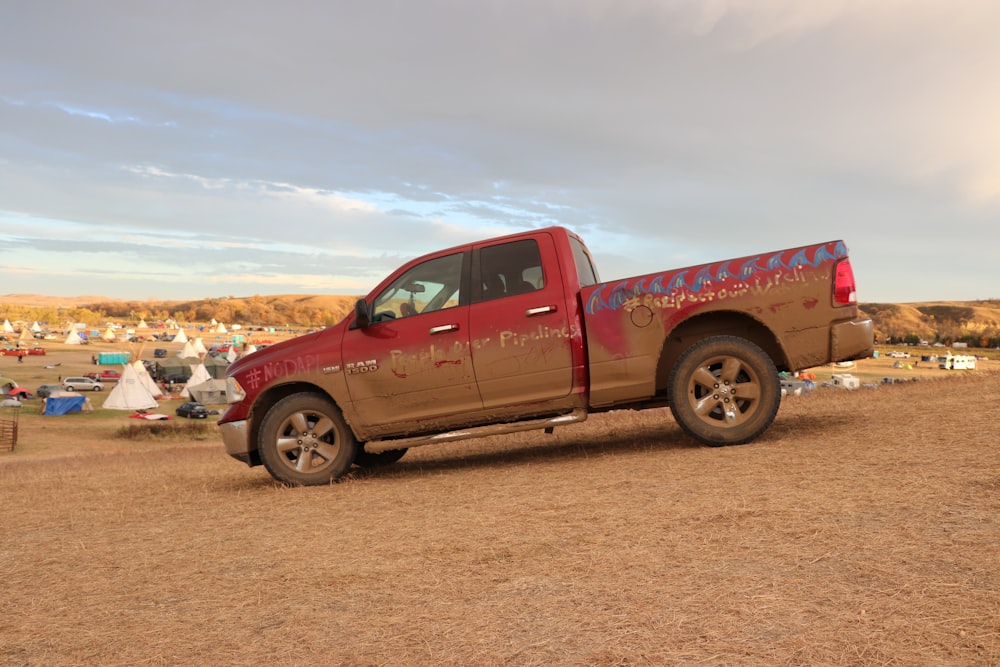 a red pickup truck parked on a dirt road