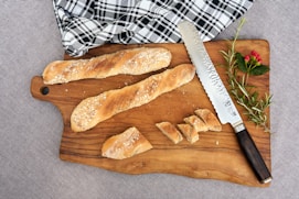 a wooden cutting board topped with bread and a knife