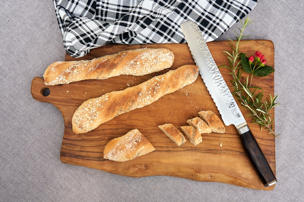 a wooden cutting board topped with bread and a knife