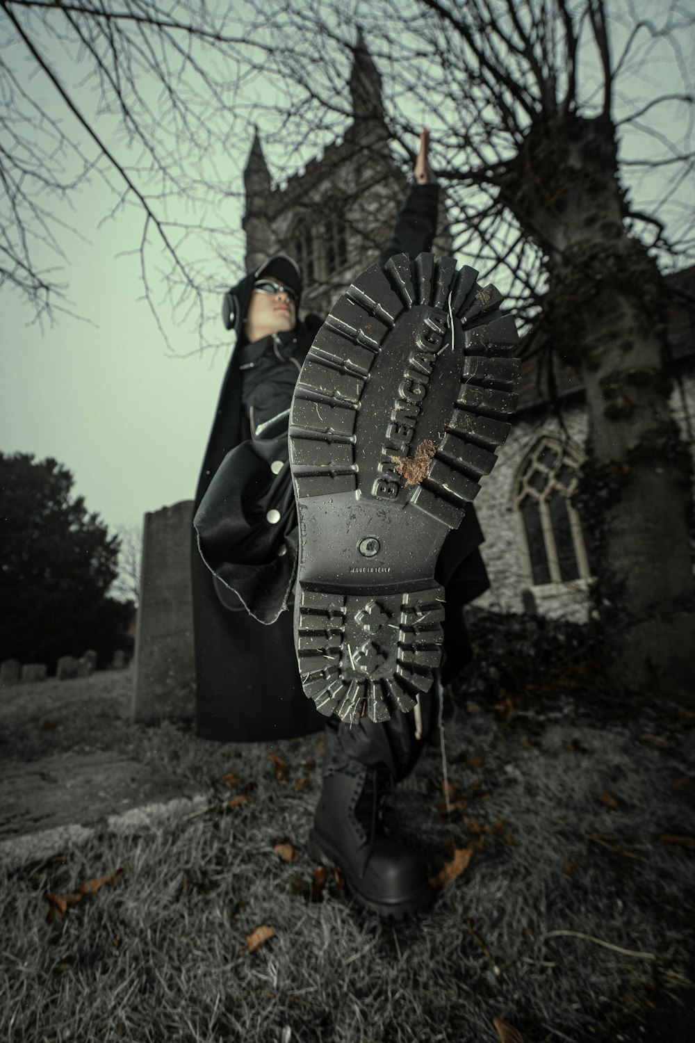 Un uomo con un mantello nero e stivali in piedi davanti a una chiesa