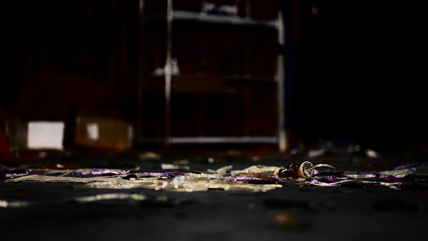 Dimly lit crime scene with scattered evidence and a shadowy figure in the background