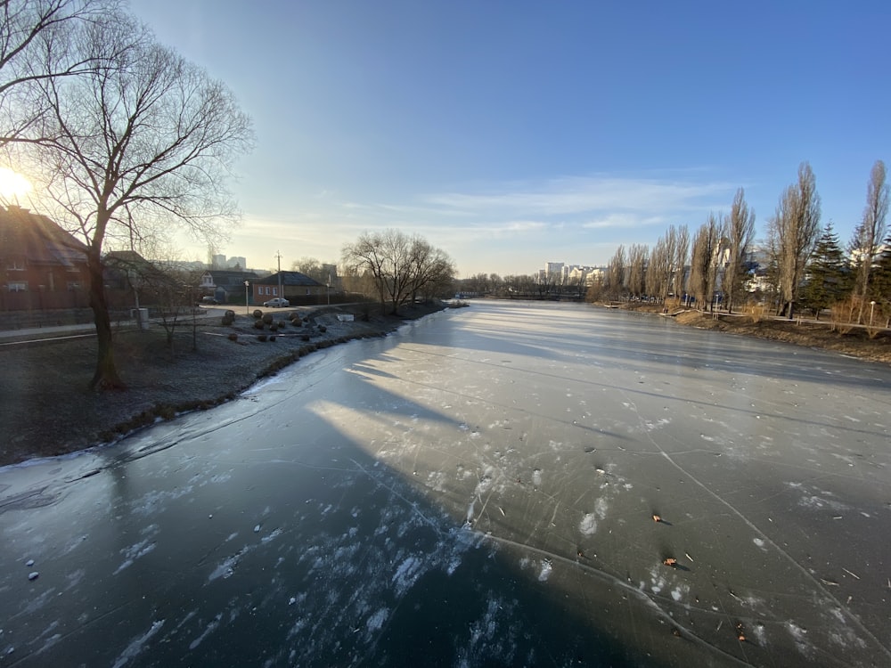 a frozen river with trees and buildings in the background