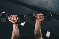 a man lifting two dumbbells in a gym