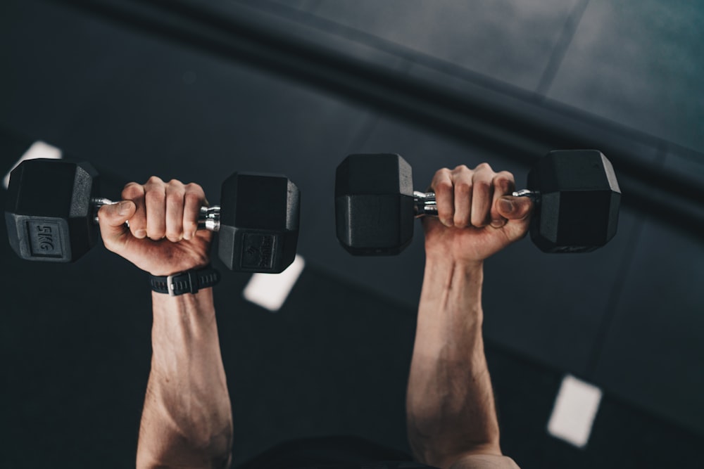 a man lifting two dumbs in a gym