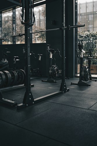 Crowded gym floor with multiple people working out independently near weight racks