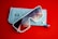 A pair of oversized sunglasses with white frames and tinted lenses rests on top of a light gray felt sunglasses case. The background is solid red, providing contrast to the case and the shades.