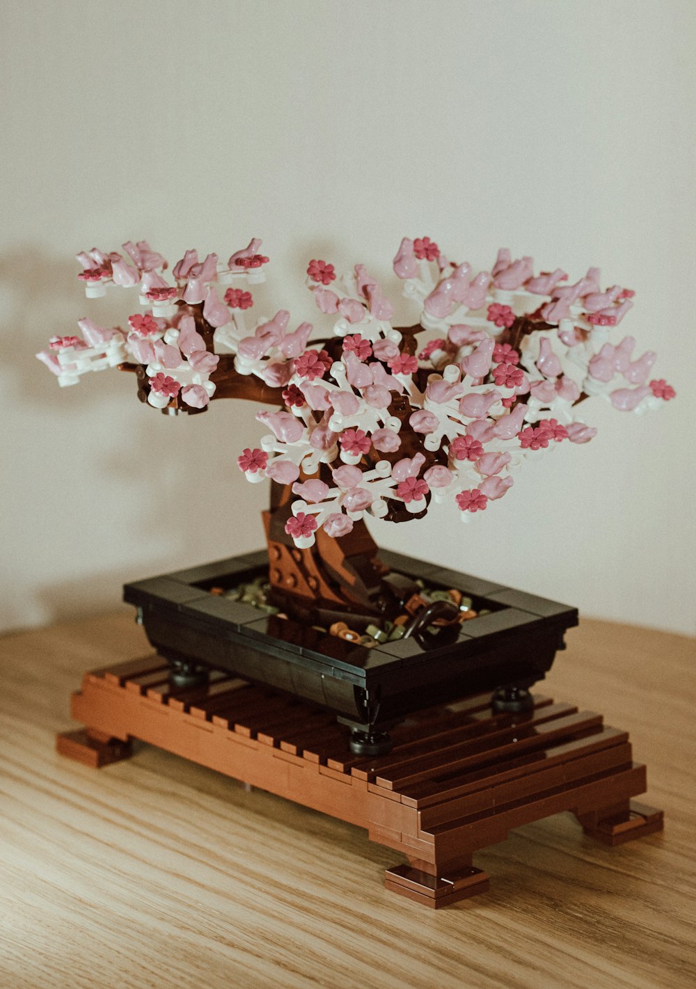 a bonsai tree with pink flowers on a wooden table