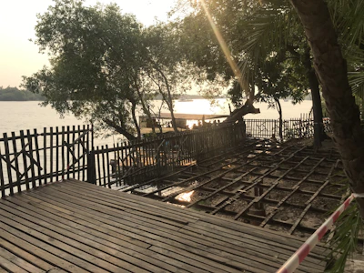 A luxurious riverside resort nestled among tall pine trees with a wooden deck overlooking flowing water.