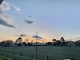 Evening view of a well-lit sports playground secured with durable mesh fencing.
