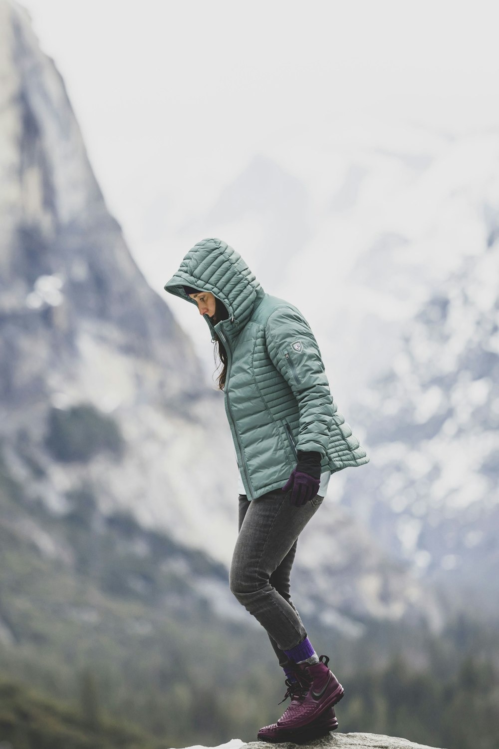 a person standing on top of a rock with a mountain in the background