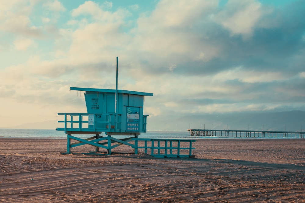 a lifeguard tower on a beach with a pier in the background