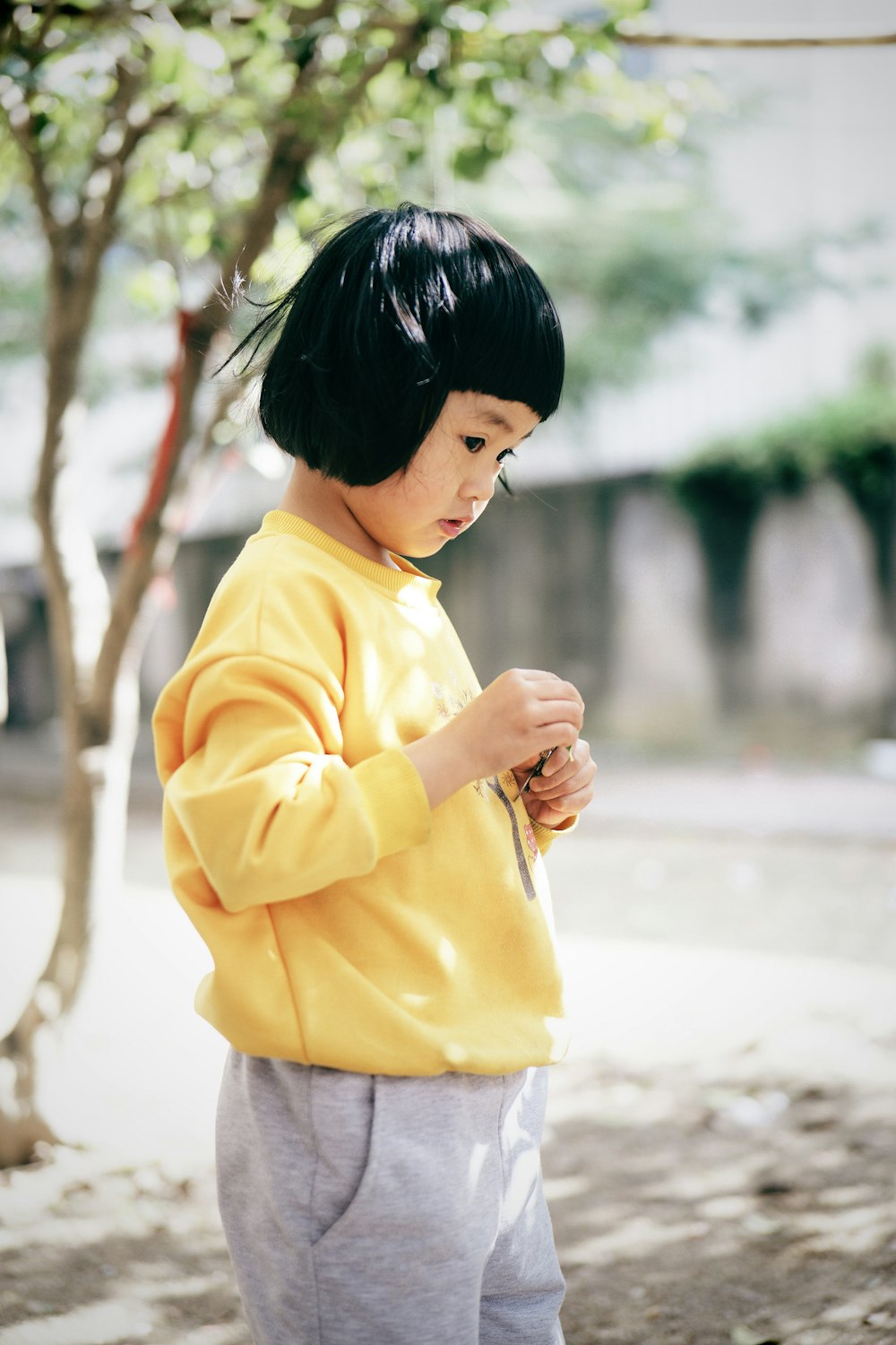 a little girl in a yellow shirt is holding something