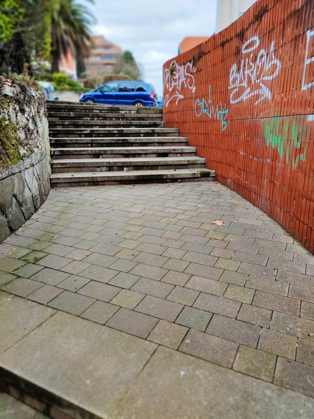 a blue car parked on the side of a brick road