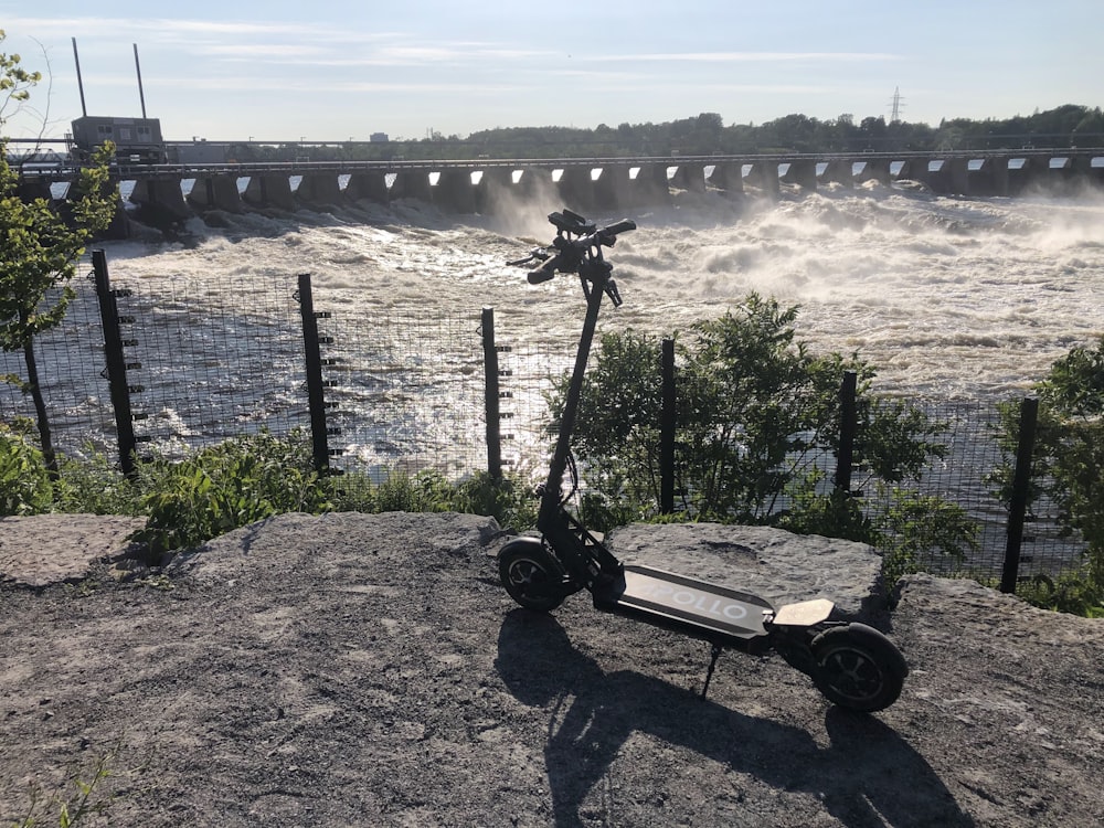 a scooter parked on top of a rock next to a body of water