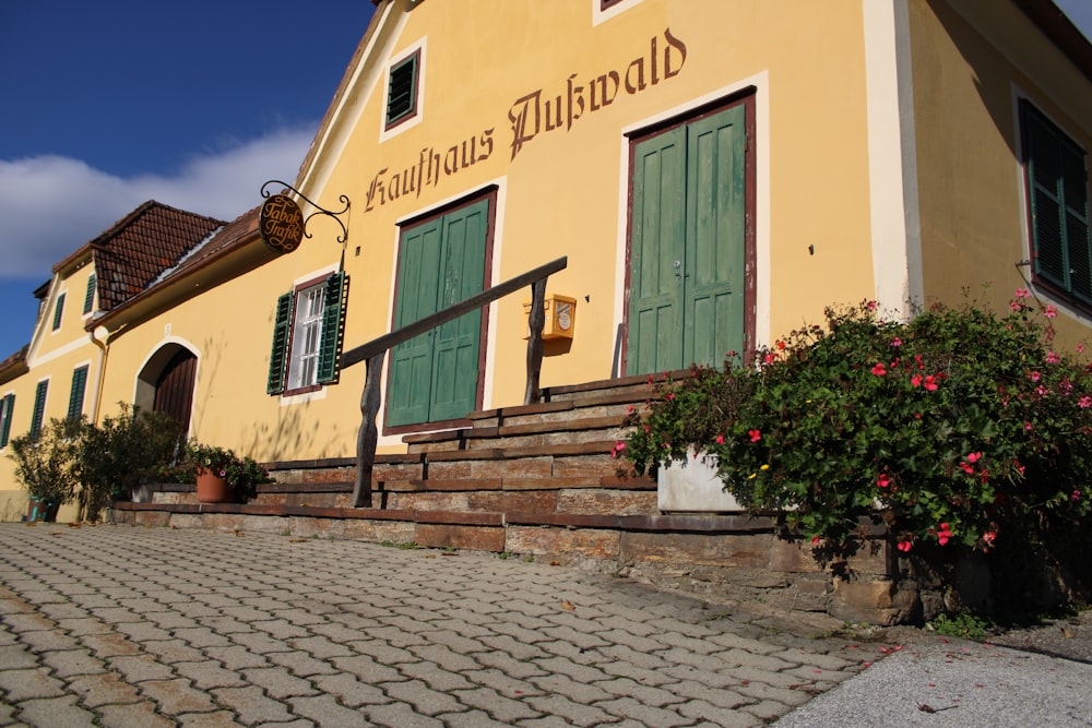 a yellow building with green doors and windows