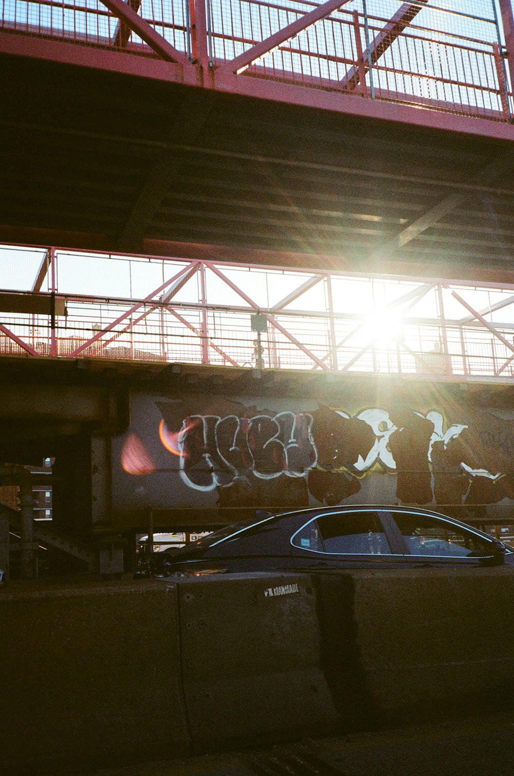 a car parked under a bridge with graffiti on it