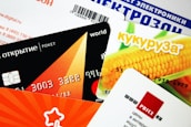A collection of colorful credit or membership cards overlapping each other, featuring various designs including a corn image, geometric shapes, and text in different languages.