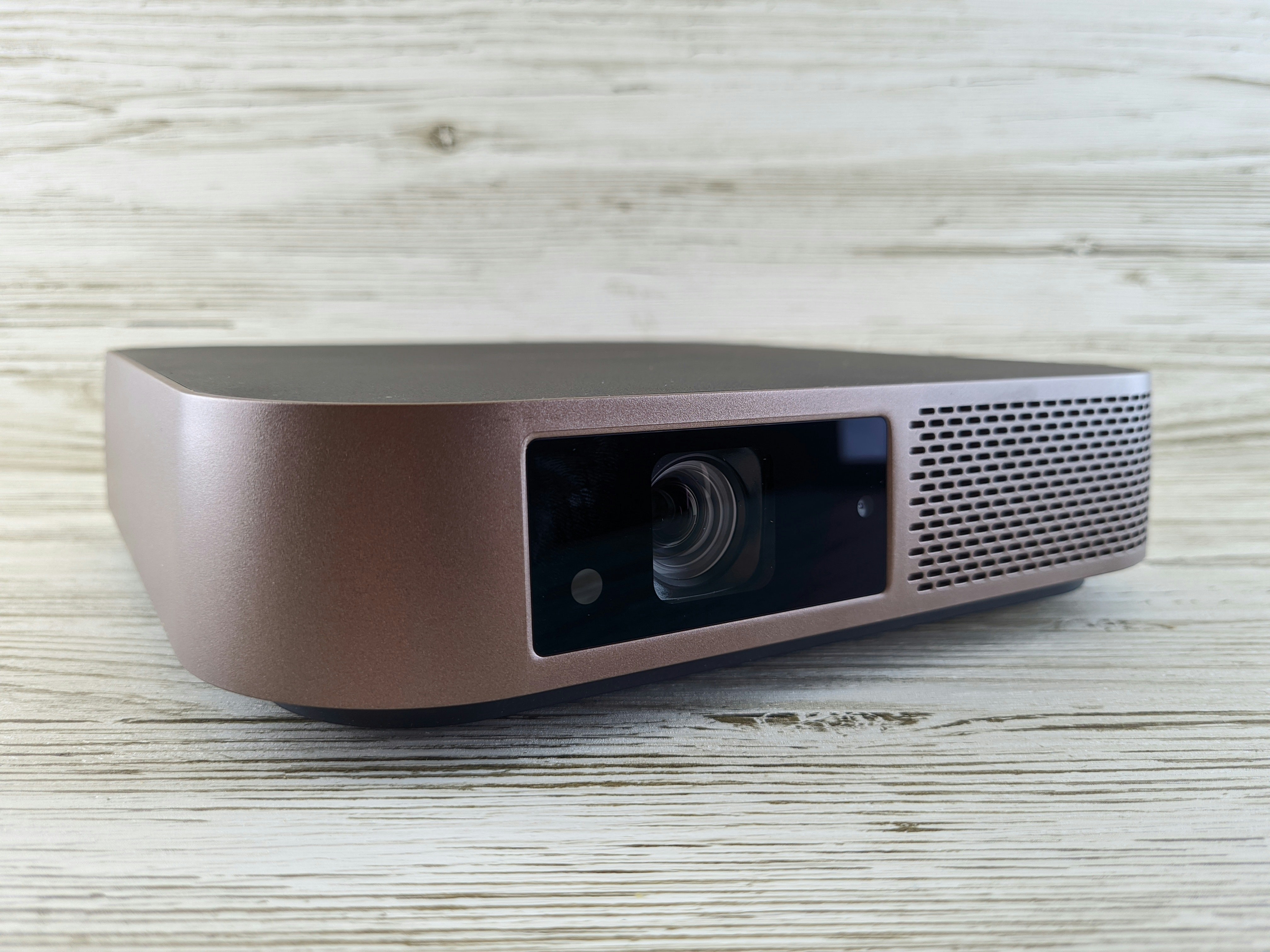 Compact white portable projector on wooden table, cinematic setup, product photography