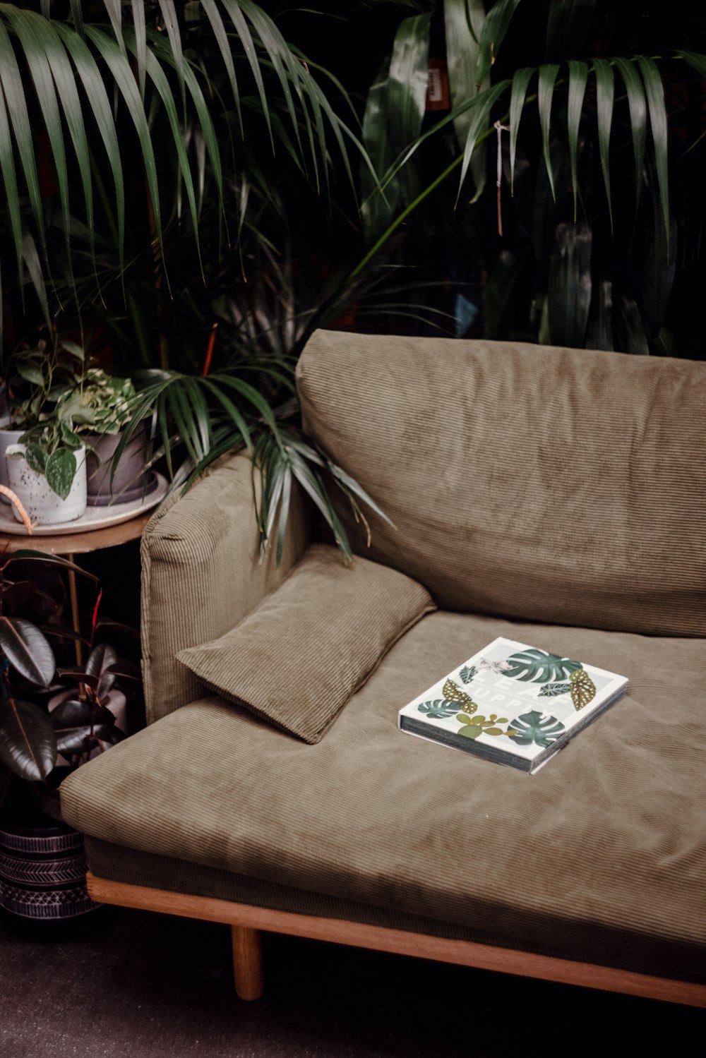 a brown couch sitting next to a table with a book on it