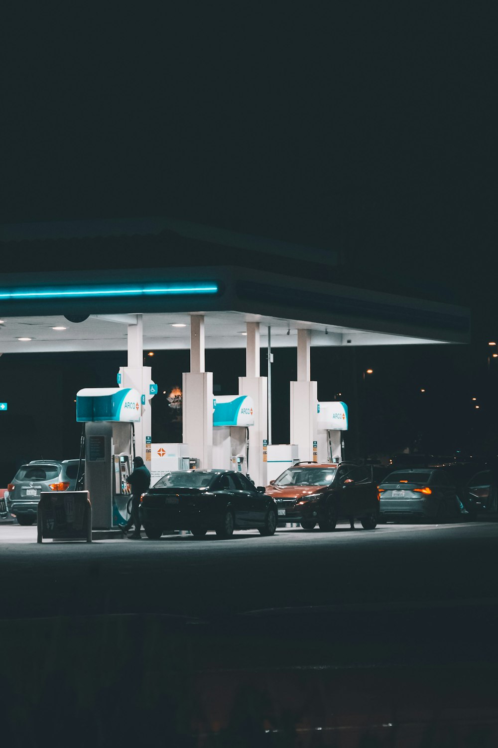 a gas station at night with cars parked in front of it