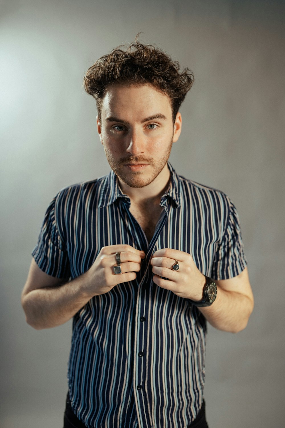 a man in a striped shirt tying his tie