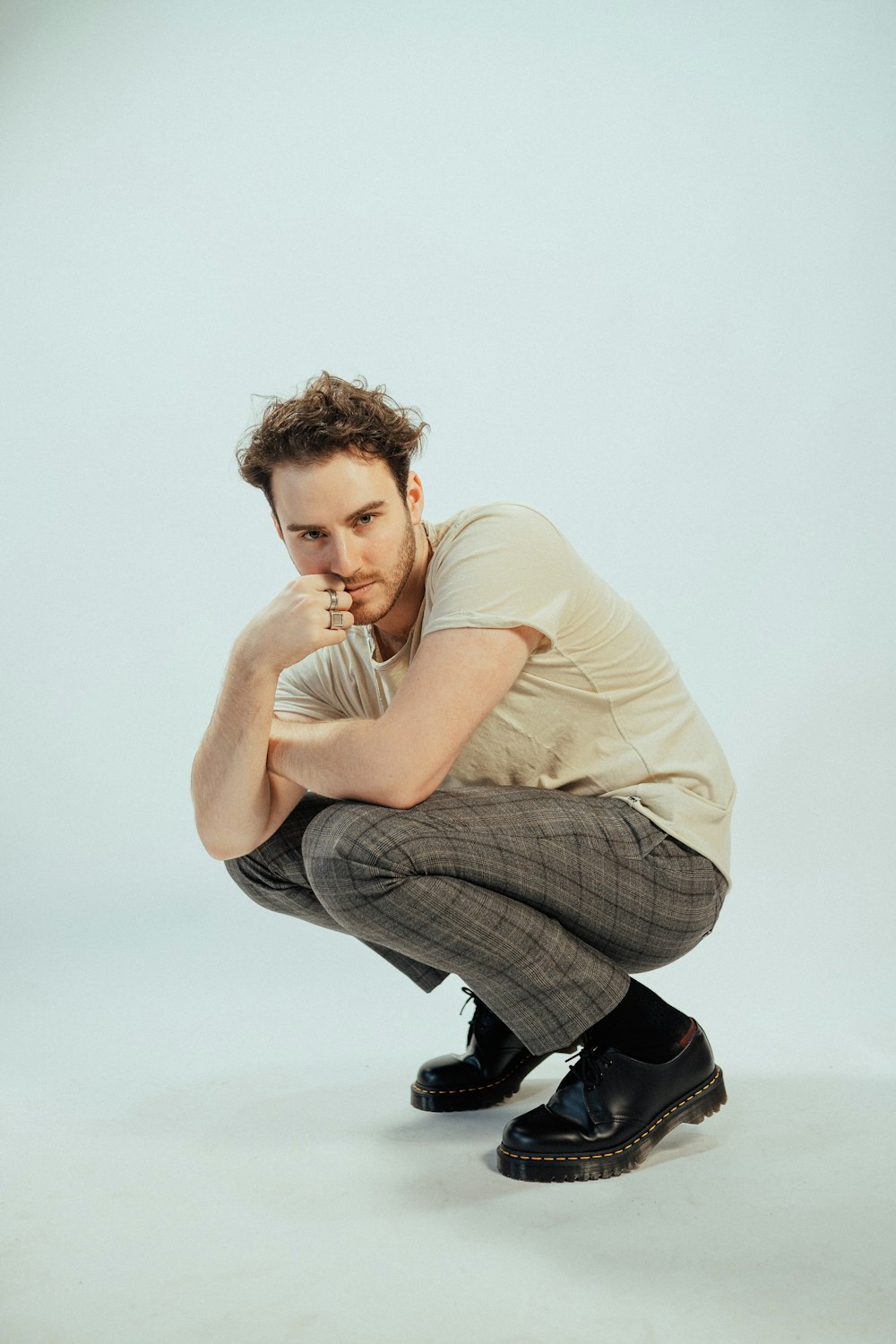 a man squatting down with his hand on his face