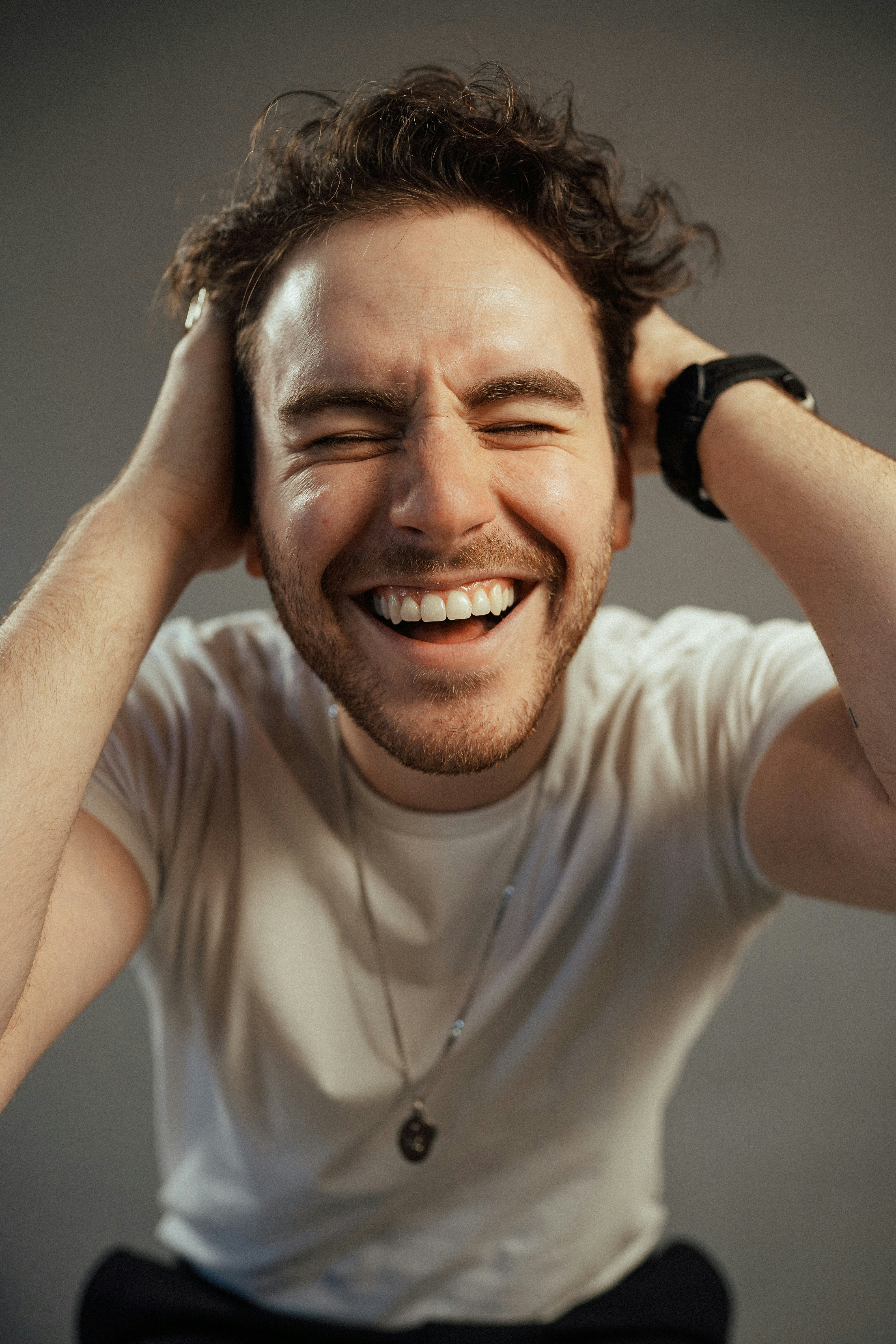 a smiling man with his hands on his head