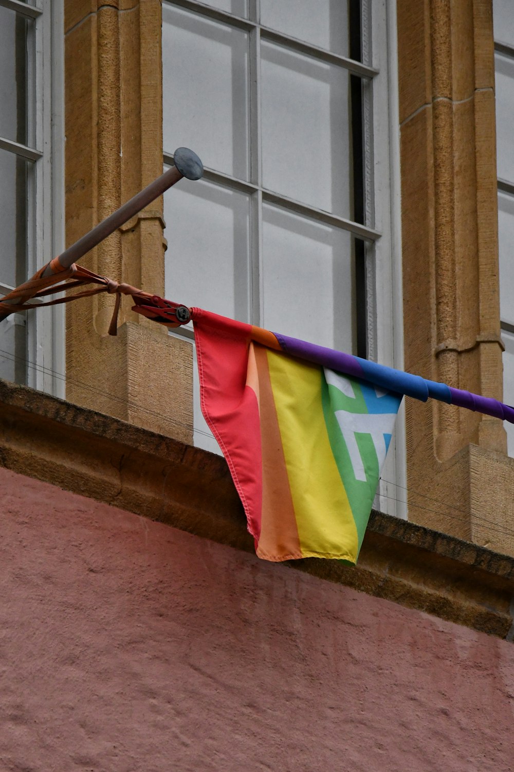 a rainbow colored flag hanging from a window sill