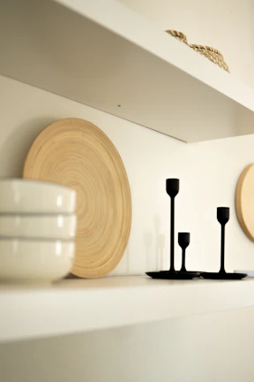 A collection of modern candles in minimalist ceramic holders arranged on a sleek shelf.