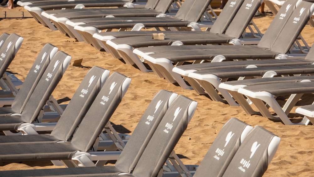 a row of chairs sitting on top of a sandy beach