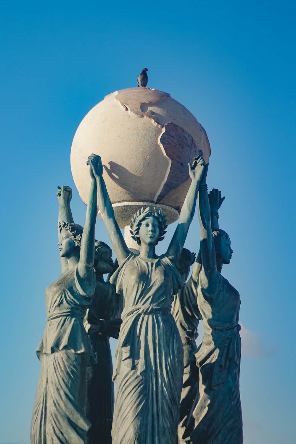 a statue of three women carrying a globe on their heads