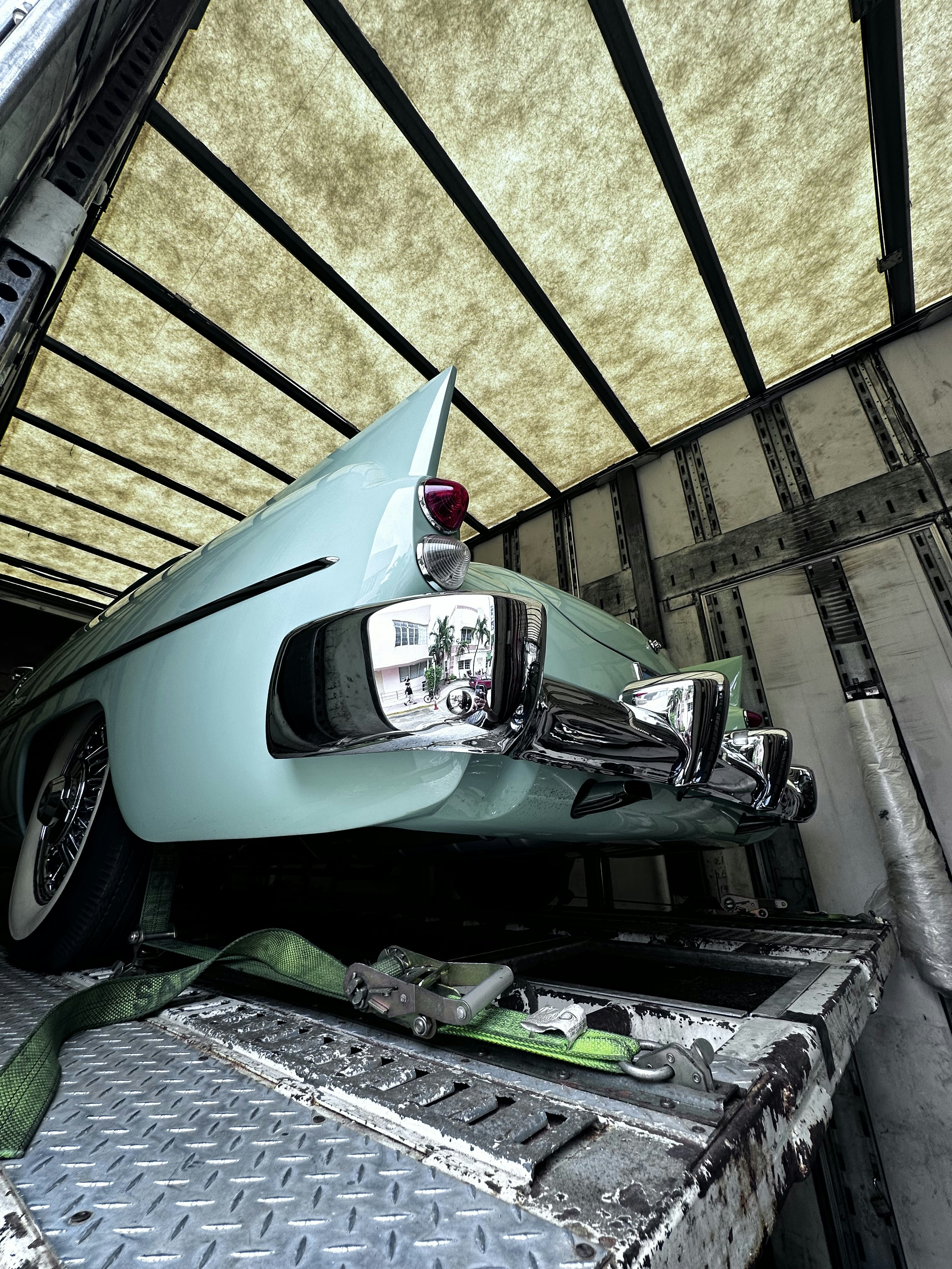 Enclosed transport trailer carrying vintage classic car with protective covering and specialized securing equipment