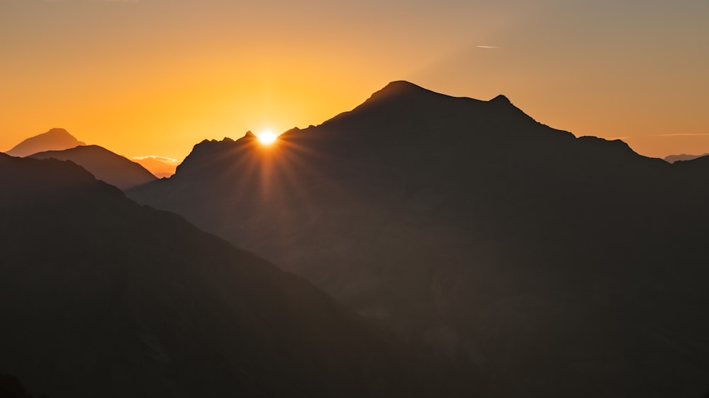 o sol está se pondo sobre uma cordilheira