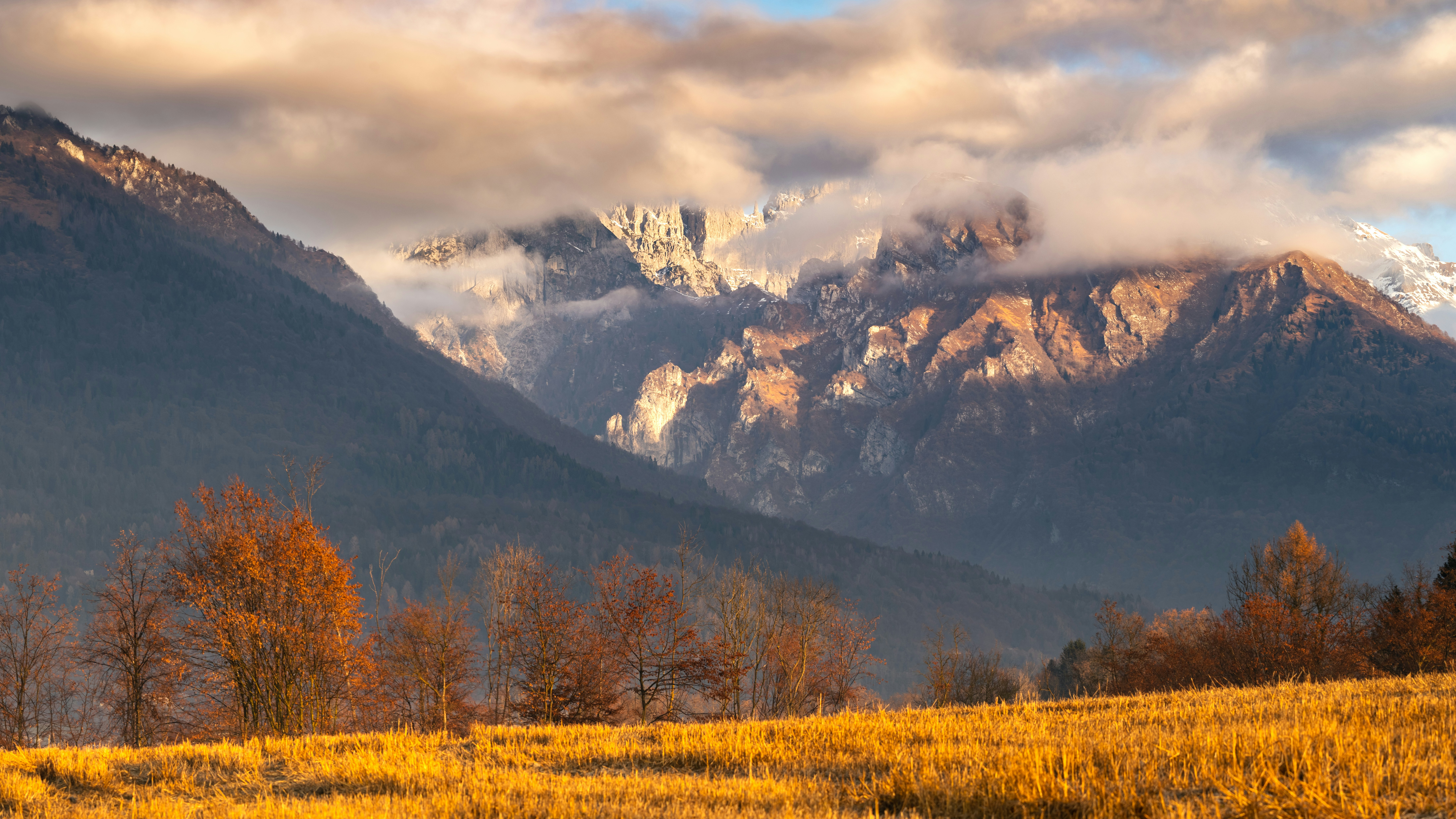 The mountains are covered in clouds and yellow grass