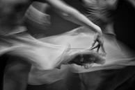 Grainy black-and-white photo capturing dancers mid-action, their movements echoing concrete architecture lines.
