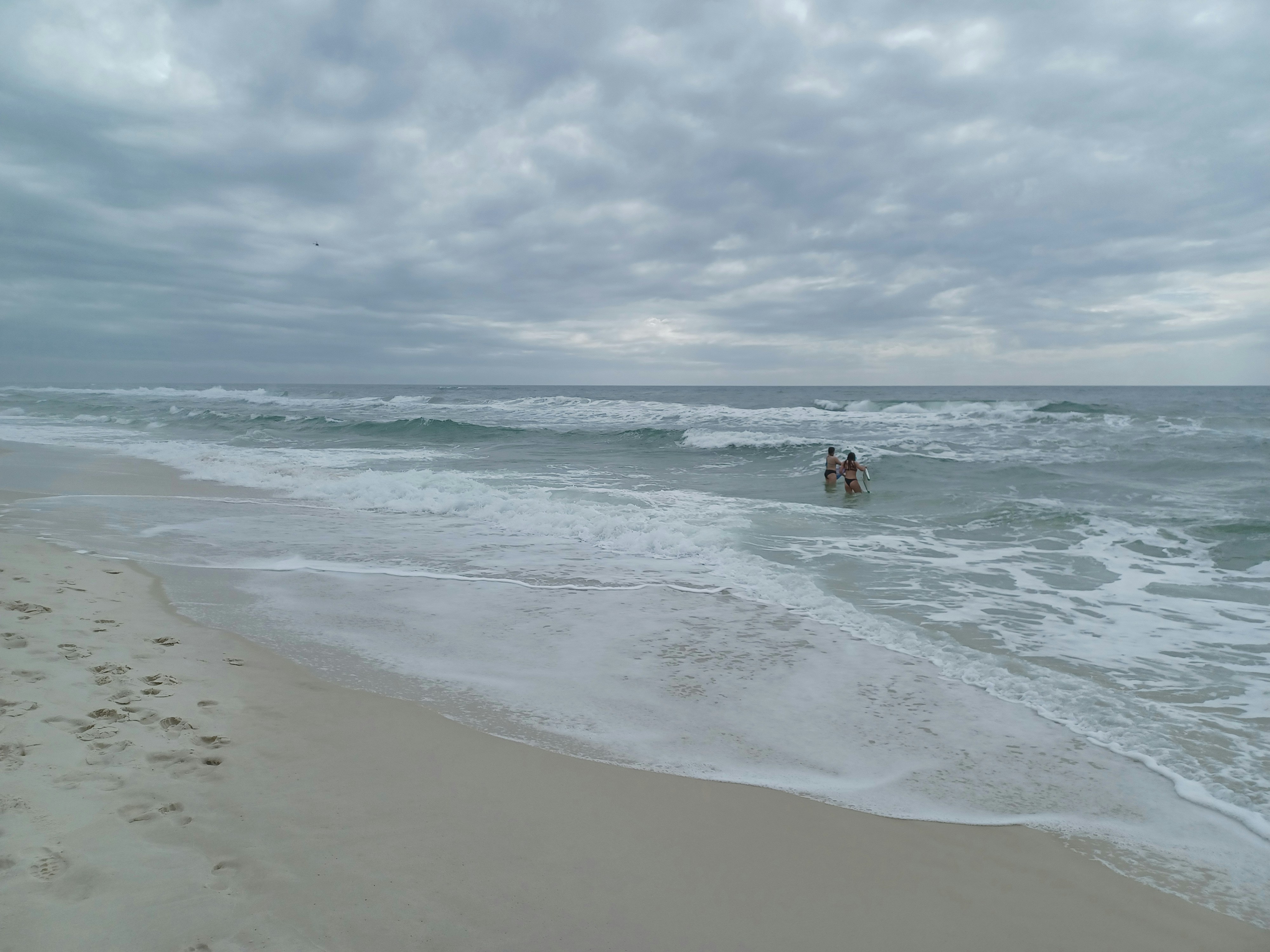 two people in the ocean on a cloudy day