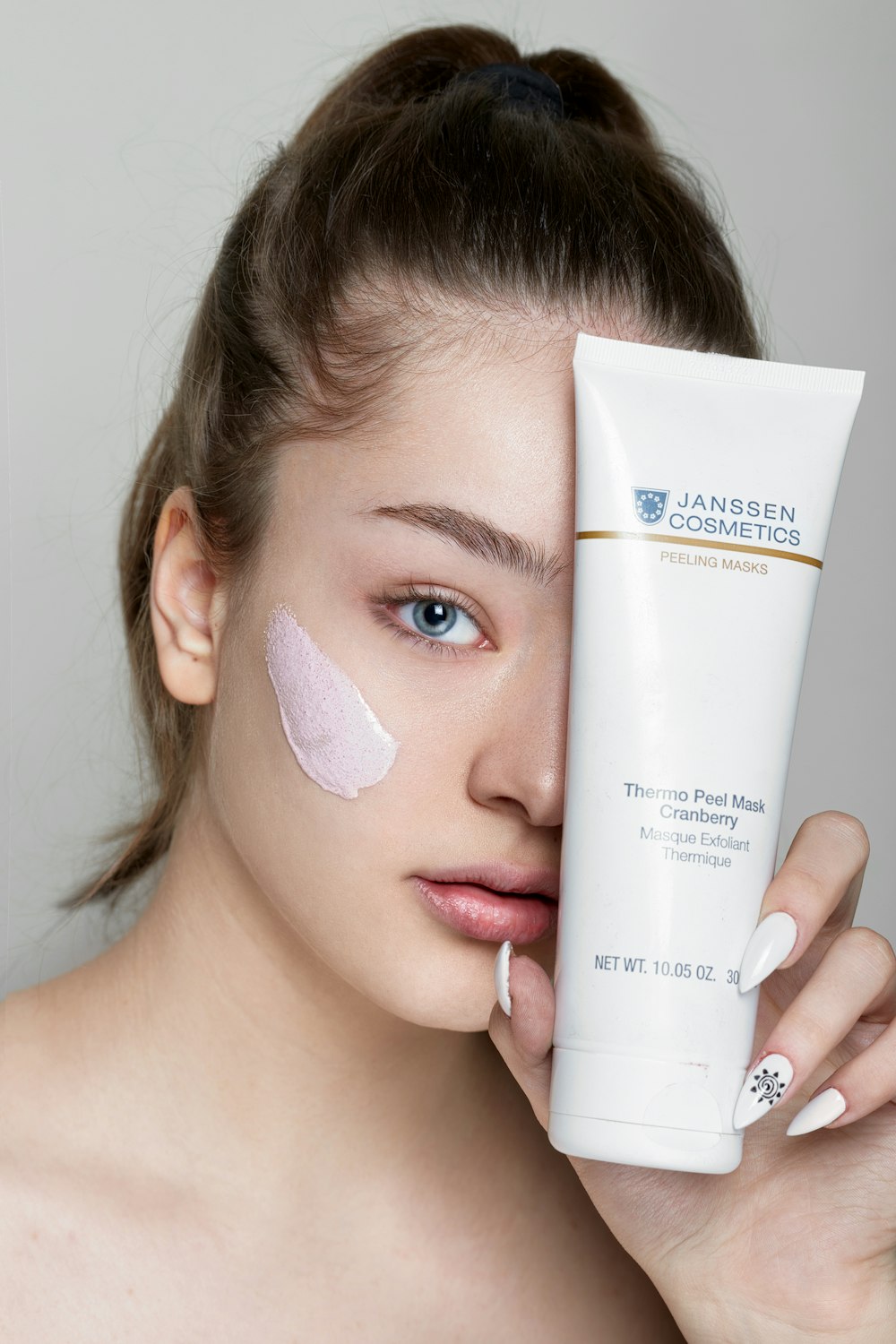 a woman holding a tube of sunscreen next to her face