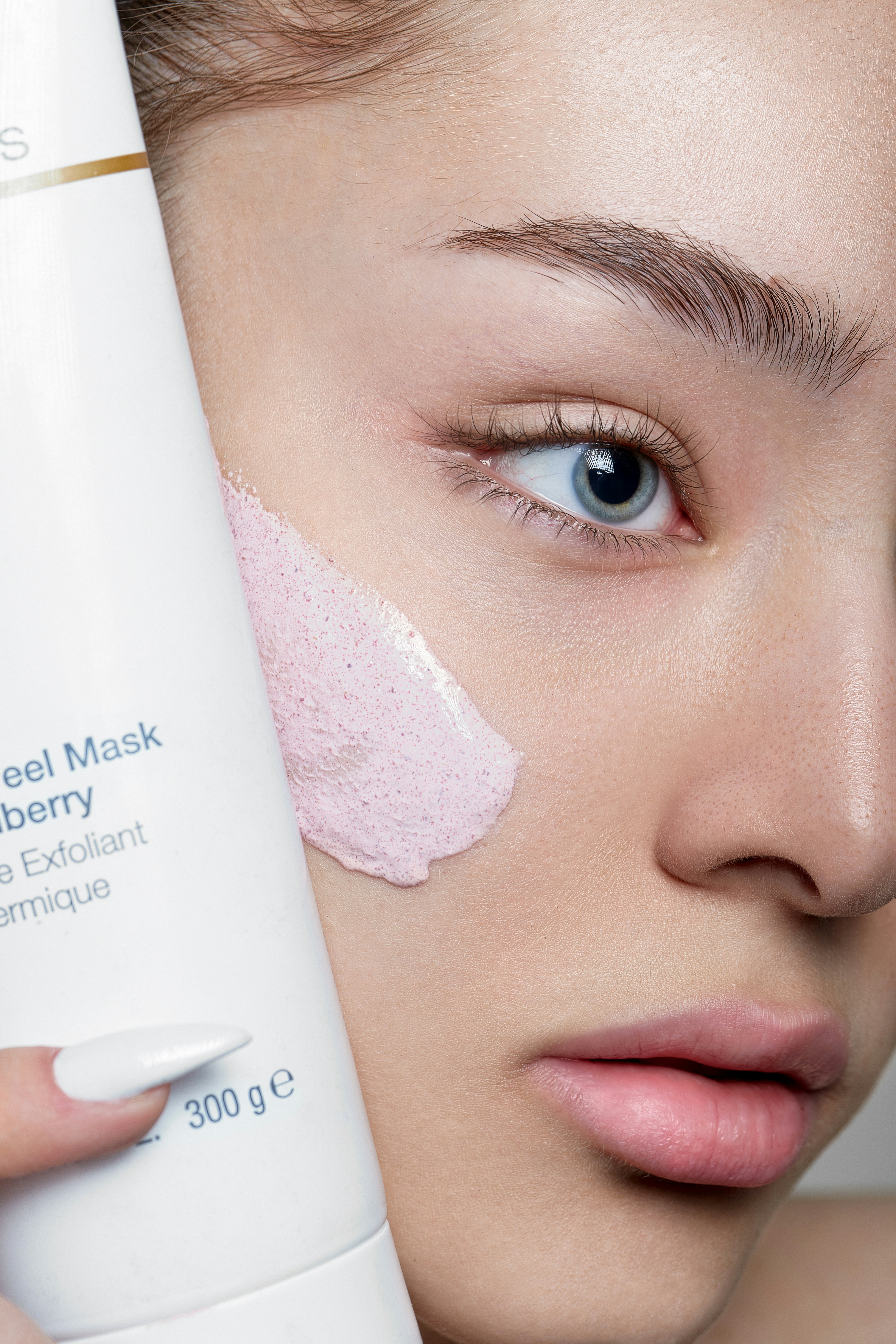 a woman holding a tube of cream on her face